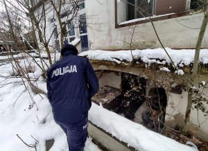 policjantka w zimowej scenerii kontroluje opuszczoną piwnicę w poszukiwaniu osób narażonych na wychłodzenie