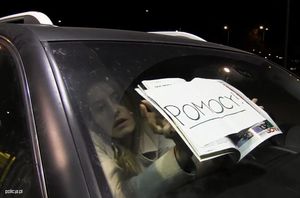 zdjęcie promujące kampanię informacyjna handlu ludźmi - kobieta w samochodzie trzyma kartkę z prośbą o pomoc