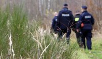 Policjanci chodzą po lesie i szukają poszukiwanego mężczyznę, który uciekł z konwoju.
