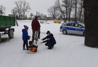 Policjantka rozmawia z dziećmi. W tle radiowóz oraz zimowa aura.